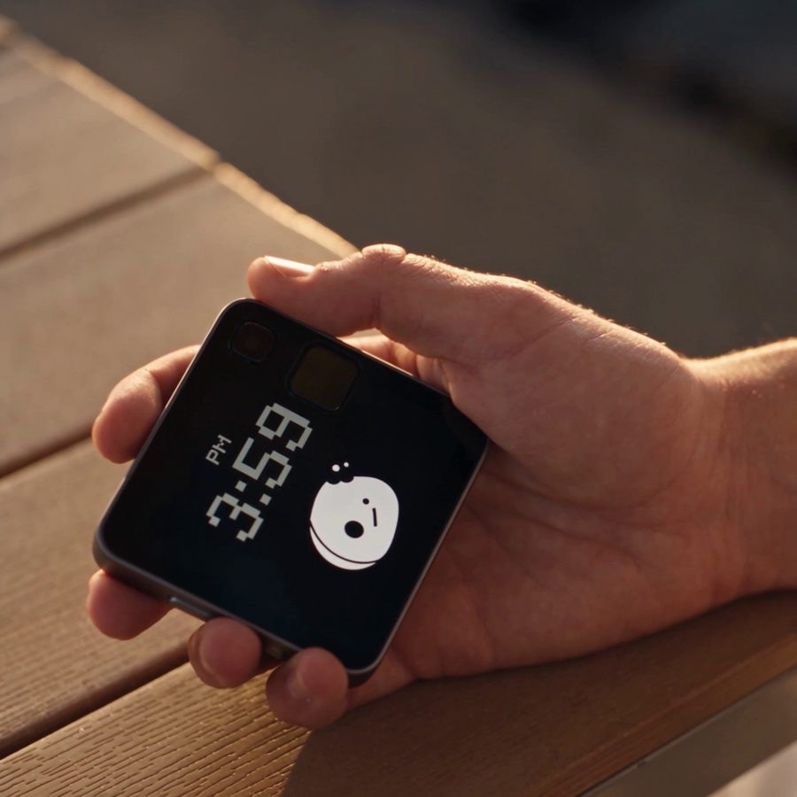 The device in a hand over a wooden table