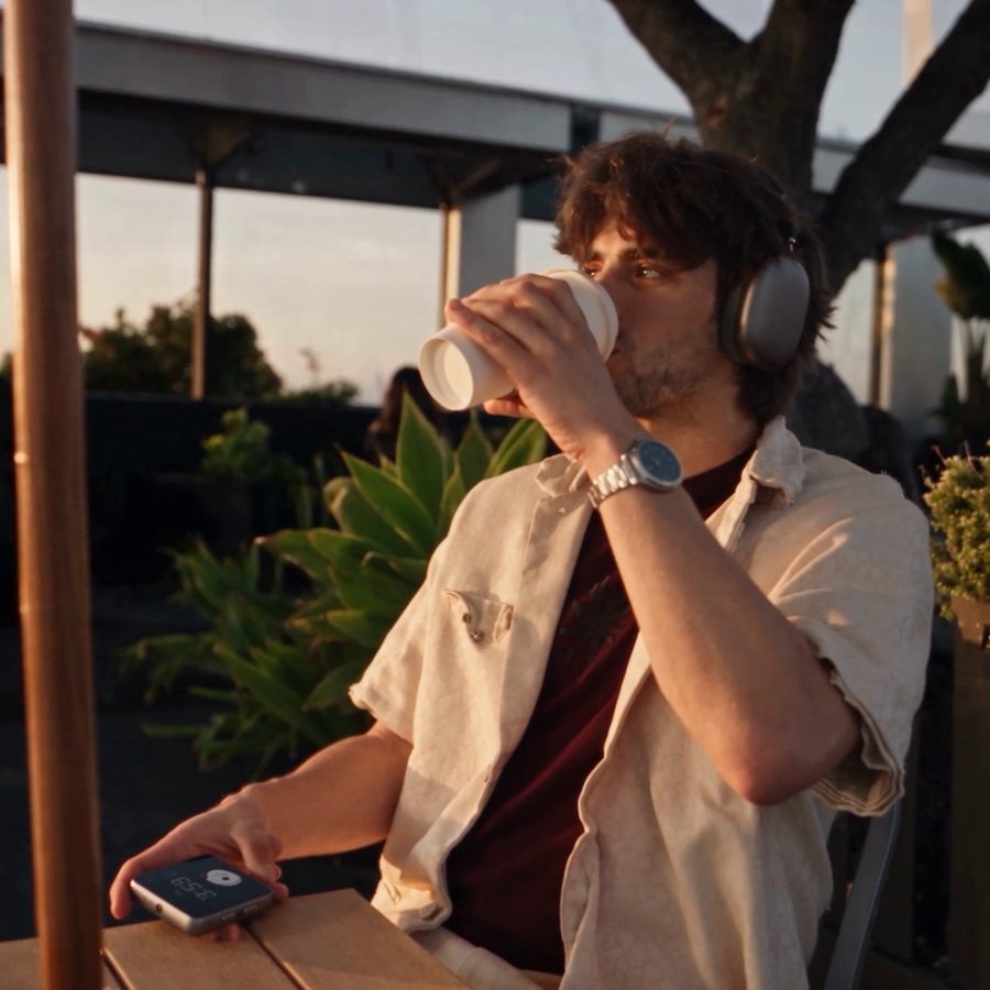 A man drinks coffee while the device lies on the table